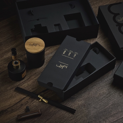 Prabangi KAM KAM dovanų dėžutė iš juodo gofruoto kartono su specialiu įdėklu, užtikrinančiu tvirtumą ir eleganciją.